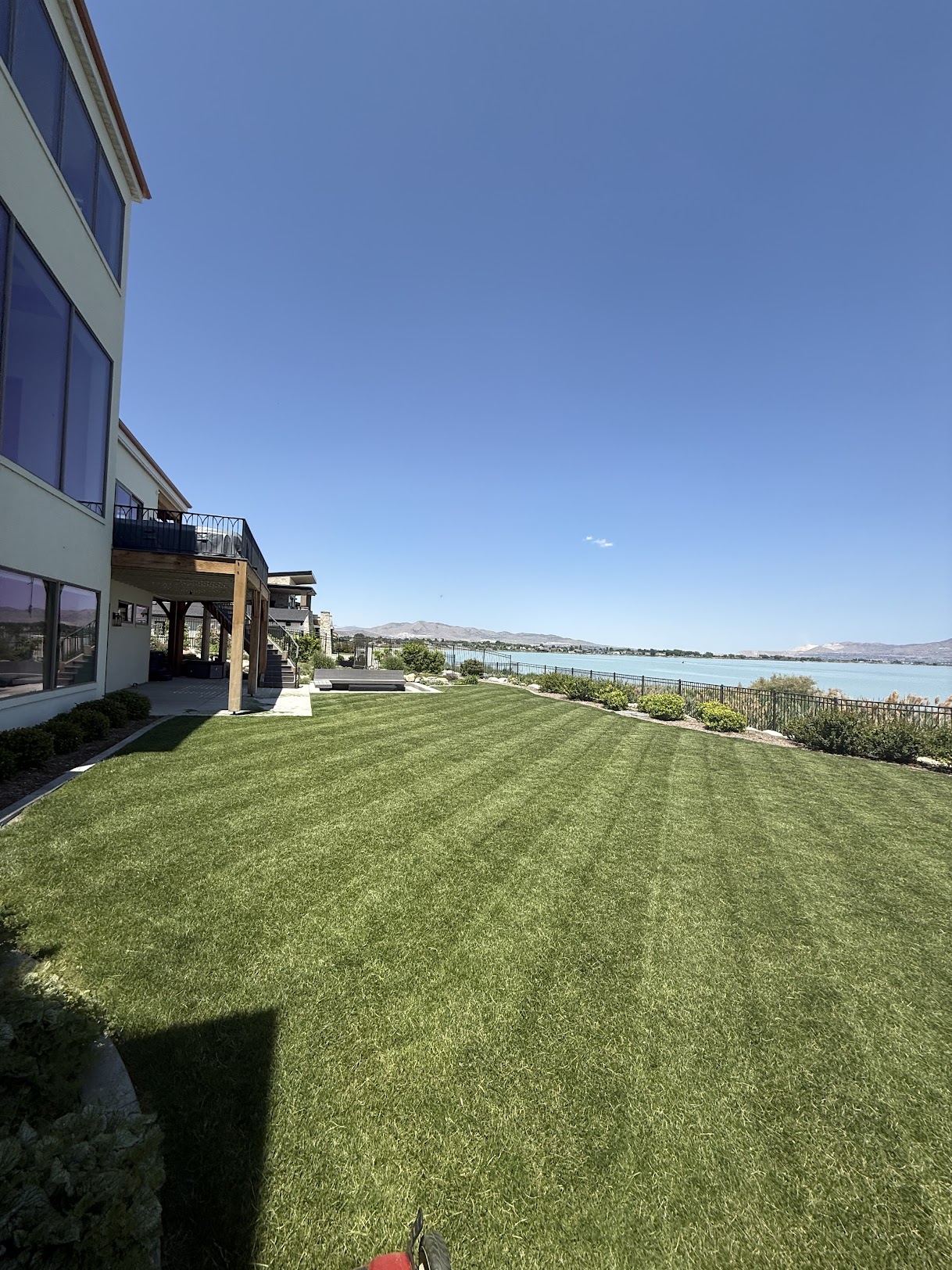 Beautiful lakefront lawn maintenance by Earthworks - perfectly striped grass with mountain lake backdrop